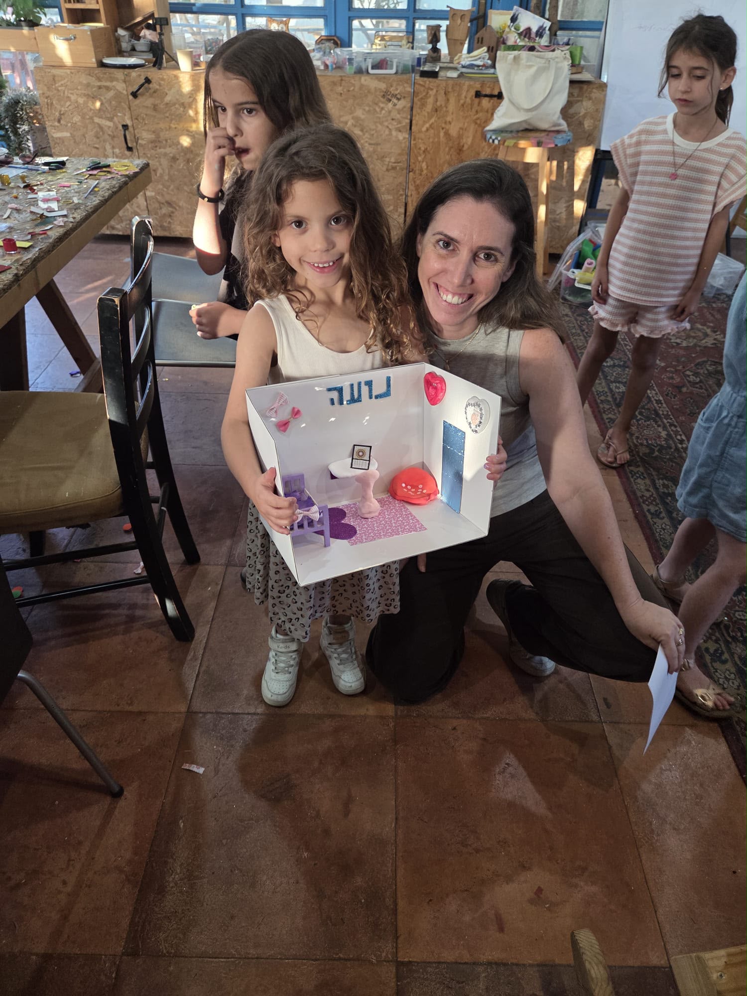 ילדה מחזיקה חדר קטן שיצרה עם שמה עליו