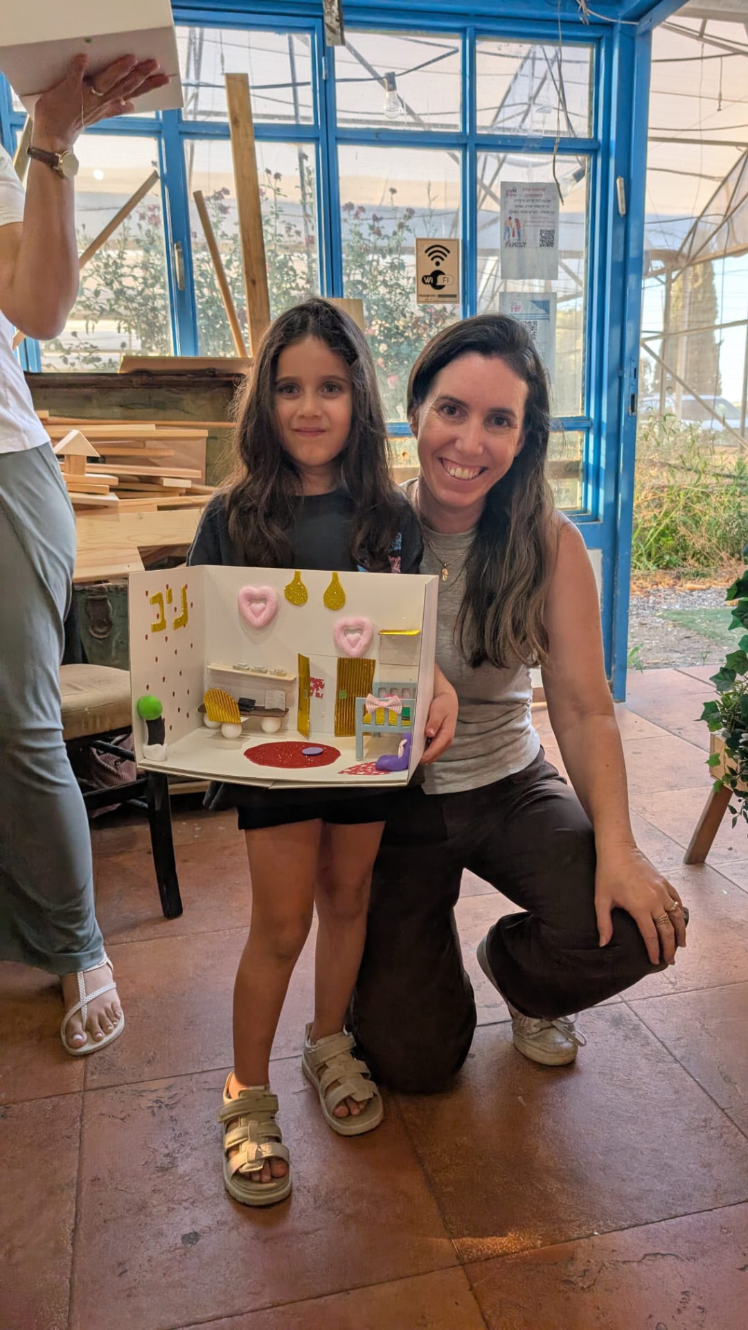 ילדה ואמא מצטלמות עם העבודה המשותפת